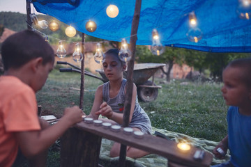 Kids making a small tent with candles and lampions in the backyard.