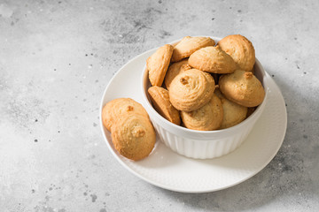 Sesame cookies in a white bowl on a light gray background
