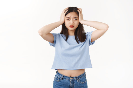 Gosh what should I do. Perplexed panicking young tired asian female student grab head panic confusion helpless situation worry how deal problems standing puzzled frustrated white wall