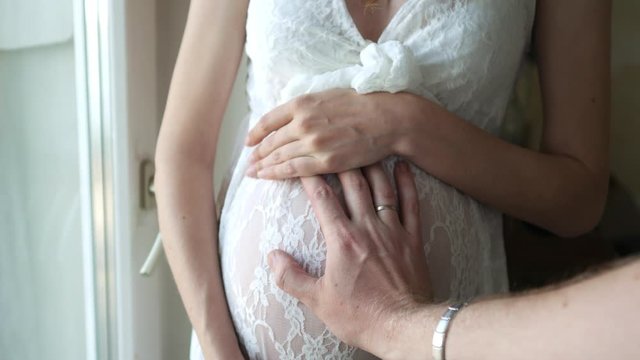 male hand holds on to the belly of a pregnant woman