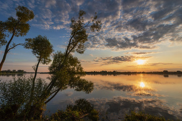 Landscape evening with sunset on a lake with lilies, with beautiful sky in summer season