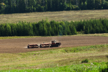 Fototapeta premium tractor cultivates field, agriculture in countryside