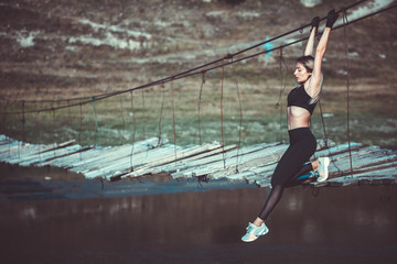 Attractive young sporty woman is working outside. Cross fit training. Muscular woman. Young, fit and beautiful girl in sporty swimsuit. Sport, diet, health and beauty concept. Young woman in black spo