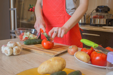 Young Woman Cooking in the kitchen. Cropped image of young girl cutting vegetables for Food. Chef cuts the vegetables into a meal