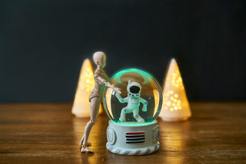 A toy astronaut meets a toy alien in a snowball.