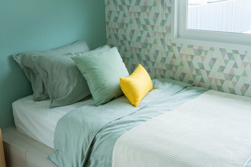 Contemporary teen bedroom with green pillow and modern side table lamp. 