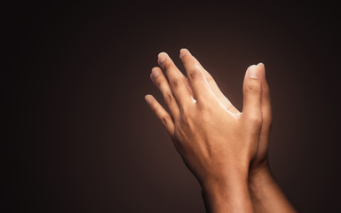 Praying hands with faith in religion and belief in God on dark background. Power of hope or love...