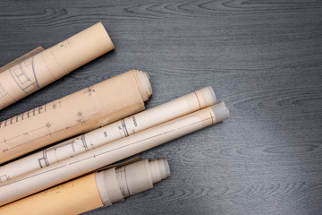 Alte Baupläne auf schwarzem Schreibtisch