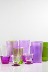 Group of various color glass on white table with a blank space for a text, glass on white background