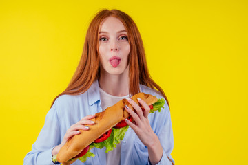 beautiful redhaired ginger woman real jam licking fingers holding huge sandwich Titanic in studio yellow background