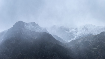 Fototapeta na wymiar Stunning moody dramatic Winter landscape image of snowcapped Y Garn mountain in Snowdonia