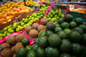 Coconuts, avocados, limes, grapefruits, oranges and mangos on the fruits and vegetables aisle in a store.