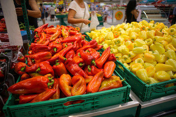 Red and yellow sweet peppers on the fruits and vegetables aisle in a store
