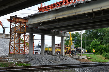 Truck crane working on a construction site. Loading cargo on a truck tractor. Reconstruction and construction of the automobile bridge, replacement of concrete slabs. Workers control work and loading