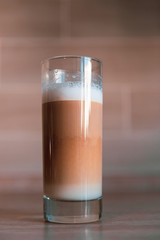 cup of multilayer coffee in a glass cup on brick background