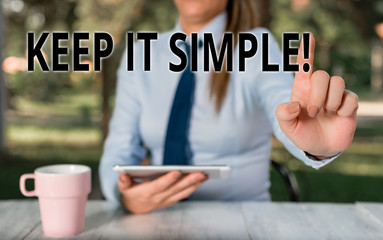 Conceptual hand writing showing Keep It Simple. Concept meaning ask something easy understand not go into too much detail Female business person sitting by table and holding mobile phone