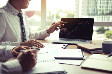 Businessman point to the laptop looking graph of the company financial statements in the computer screen and together analysis the work room.