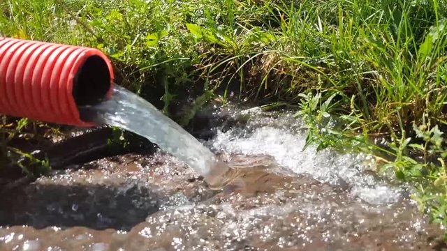 Orange plastic rainwater drainage system with stormwater flowing down the drain. Video about wastewater. Slow motion water splashes