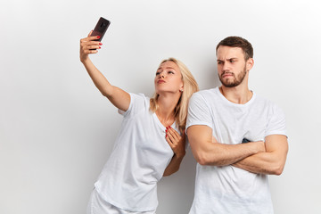 Portrait of young handsome unhappy man with crossed arms doen't want to take selfie with his...