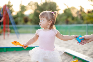 baby girl playing in sandbox in kindergarten.ittle girl plays with toys in the sand. The concept of...