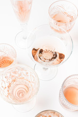 Sparkling rose wine in different glasses on white background