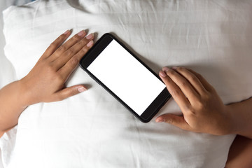 Asian Woman's hands using smartphone with blank screen in bedroom at morning.