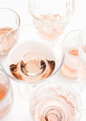 Sparkling rose wine in different glasses on white background