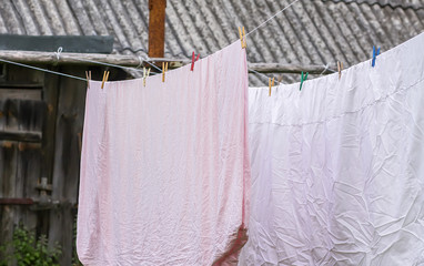 Freshly washed bed linen hanging on the rope outdoors.