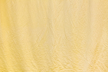 Crumpled soft light yellow bed linen surface