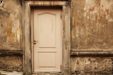 Old aged white door in weathered dirty wall