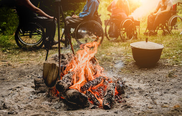 Group of disabled persons resting in a campsite with friends. Wheelchair in the forest on the...
