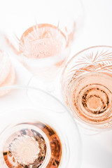 Sparkling rose wine in different glasses on white background