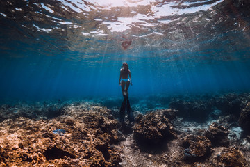 Woman freediver with fins glides underwater in sea