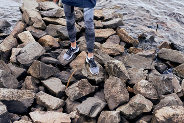 Female sportsman feet standing on rocky lake bank