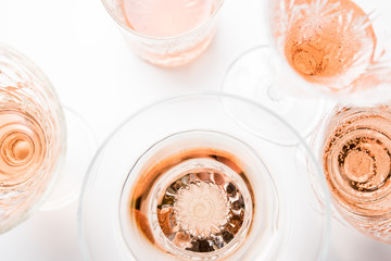Sparkling rose wine in different glasses on white background