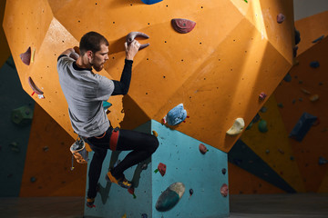 Man with physical disability rock climbing during his morning training at bouldering sport center, enjoys his extreme hobby and achieves great results. Low angle view. Active lifestyle concept.