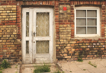 Old white wooden door in weathered dirty brick wall