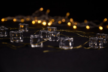 several cubes of ice on golden threads and with a background of blurred golden lights