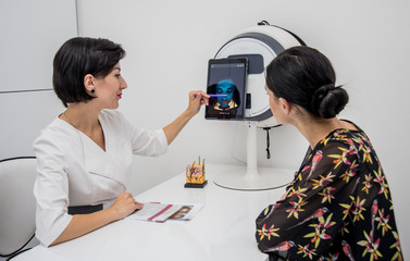 Face skin analyze system. Cosmetologist analyzing woman face. Modern technologies.