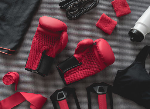 top view of boxing gym concept with boxing glove, Gym Outfit, skipping rope and accessories on yoga mat background.