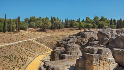 Fototapeta na wymiar Land and ruins of the amphitheater, part of archaeological ensemble of Italica, city with a strategic role in the Roman Empire, birthplace of Emperors Trajan and Hadrian, in Santiponce, Seville, Spain