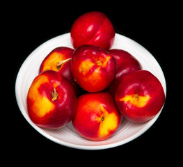 Ripe nectarine in a white plate on a black background