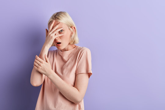 beautiful girl with palms on her face watching horrror movie, close up photo. woman hiding behind her palms. copy space.