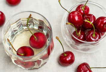 Red cherries in glass plates and white wine in a glass