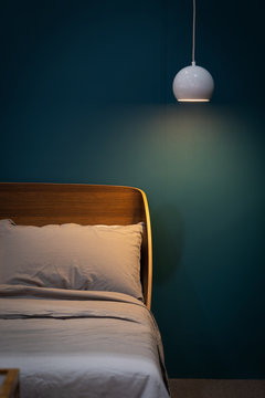 White Bed And Gray Pillow With Wooden Headboard Against Dark Blue Bedroom