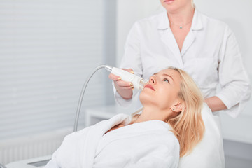 young female patient in white bathrobe having beauty medical treatment, close up side view photo,...