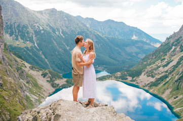Naklejka premium Happy loving couple standing together at stone in High Tatra national park in Poland with a picturesque landscape on background.