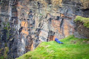 Mujer asomándose al acantilado de Moher, Irlanda