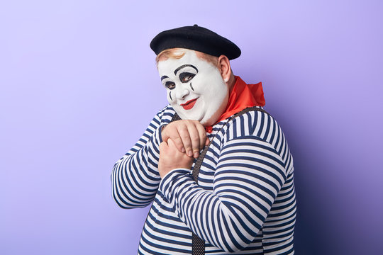 friendly kind clown in striped sweater, red kerchief around neck and black hat expresses tender feeling, sweetheart.