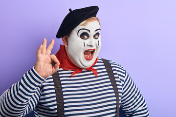 funny fat man in stiped sweater and black beret expresses agreement. close up portrait, body...